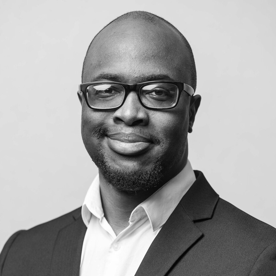 Young black man wearing a suit and glasses smiling
